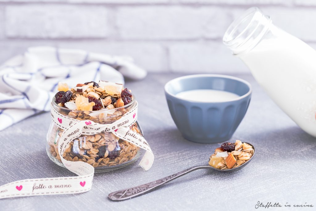 La granola esotica allo zenzero ci accompagna in tutte le nostre colazioni estive. È perfetta per arricchire una tazza di latte, uno yogurt greco, o per decorare una smoothie bowl. Provate per esempio la nostra Smoothie bowl alle fragole. La ricetta di questa granola esotica allo zenzero si ispira a quella che trovate nel libro Pancetta Bistrot delle nostre amiche Laura e Sara. La ricetta di base è la stessa, ma noi siamo molto golose e ci piacciono le granole ricche, quindi oltre alle chips di cocco abbiamo aggiunto anche cranberries essiccati e zenzero candito, dalla caratteristica piccantezza. Dallo stesso libro abbiamo tratto la ricetta delle Frittelle di feta e pomodoro. Per la preparazione di questa granola è necessario lo sciroppo d’acero. Altre idee per utilizzarlo sono i classicissimi Pancakes, perfetti per una ricca colazione, oppure la Pavlova alla cannella con frutti rossi, dove dà un tocco in più a questo dolce raffinato ed elegante.